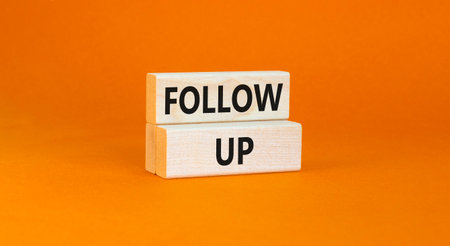Follow up symbol. Concept word Follow up on beautiful wooden blocks. Beautiful orange paper background. Business follow up concept. Copy space.の写真素材