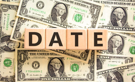 Date symbol. Concept word Date on beautiful wooden blocks. Dollar bills. Beautiful background from dollar bills. Business and date concept. Copy space.の写真素材