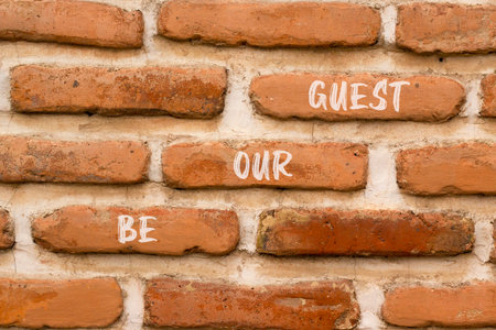 Be our guest symbol. Concept words Be our guest on beautiful brown brick wall. Beautiful brown brick wall background. Business and be our guest concept. Copy space.の写真素材
