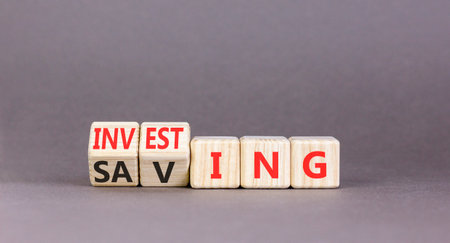 Investing and saving symbol. Concept words Saving to Investing on beautiful wooden cubes. Beautiful gray table gray background. Business, investing and saving concept. Copy space.の写真素材