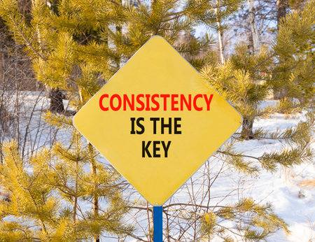 Consistency is the key symbol. Concept words Consistency is the key on beautiful yellow road sign. Beautiful winter forest background. Business consistency is the key concept. Copy space.の写真素材