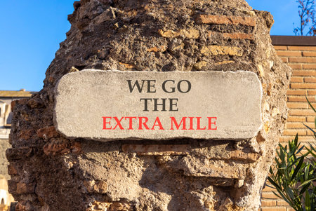 Support, help we go the extra mile symbol. Concept words We go the extra mile on beautiful white marble sign plate. Beautiful brick column background. Business we go the extra mile concept. Copy spaceの写真素材