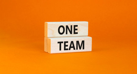One team symbol. Concept word One team on beautiful wooden blocks. Beautiful orange paper...
