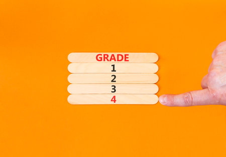 Time to grade 4 symbol. Concept word Grade 1 2 3 4 on beautiful wooden sticks. Businessman's hand. Beautiful orange background. Business planning and time to grade 4 concept. Copy space.の写真素材