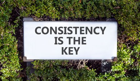 Consistency is the key symbol. Concept words Consistency is the key on white beautiful road sign. Beautiful green trees background. Business consistency is the key concept. Copy space.の写真素材