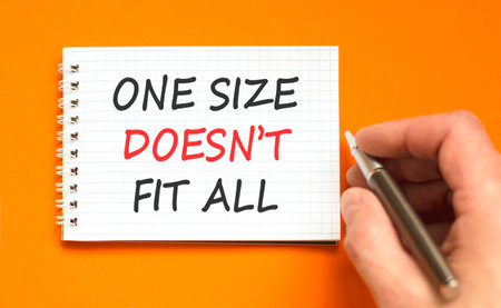 One size does not fit all symbol. Concept words One size does not fit all on beautiful note. Beautiful orange background. Businessman's hand. Business one size does not fit all concept. Copy space.の写真素材