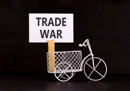 Trade war symbol. Concept word Trade war on beautiful white paper. Beautiful wooden clothespin. Miniature white bicycle. Beautiful black background. Business trade war concept. Copy space.の写真素材