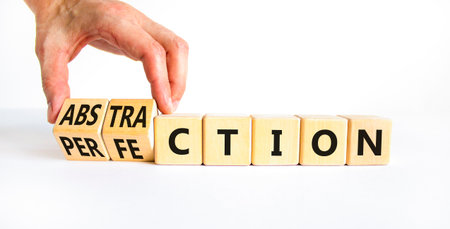 Perfection or abstraction symbol. Concept words Perfection Abstraction on beautiful wooden blocks. Beautiful white background. Businessman hand. Business perfection or abstraction concept. Copy spaceの写真素材
