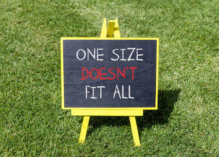 One size does not fit all symbol. Concept words One size does not fit all on beautiful blackboard. Beautiful green grass lawn background. Business one size does not fit all concept. Copy space.の写真素材