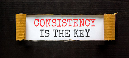 Consistency is the key symbol. Concept words Consistency is the key on beautiful white paper. Beautiful black paper background. Business consistency is the key concept. Copy space.の写真素材