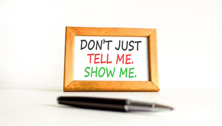 Tell or show symbol. Concept words Do not just tell me, show me on beautiful wooden picture frame. Beautiful white background. Black pen. Business tell or show concept. Copy space.の写真素材