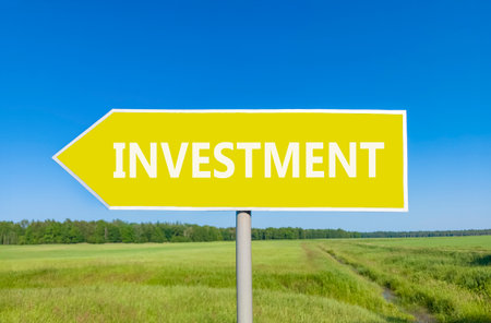 Investment symbol. Concept word Investment on beautiful yellow road sign. Beautiful blue sky green...
