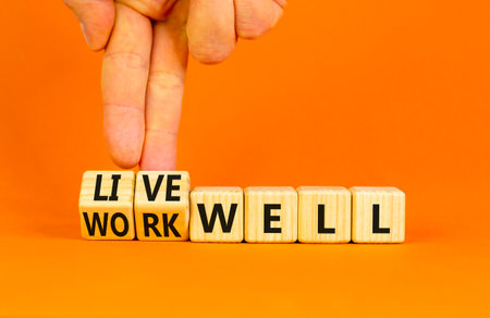 Live or work well symbol. Concept words Live well Work well on wooden cubes. Beautiful orange table orange background. Businessman hand. Business and live or work well concept. Copy space.の写真素材