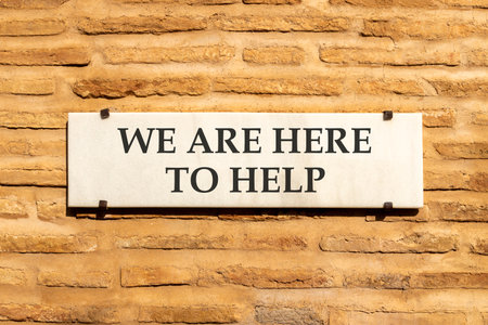 Support, help and we are here to help symbol. Concept words We are here to help on beautiful white marble sign plate. Beautiful brick wall background. Business we are here to help concept. Copy space.の写真素材