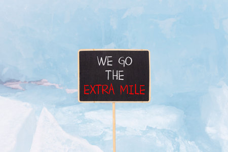 Support, help we go the extra mile symbol. Concept words We go the extra mile on beautiful blackboard. Beautiful blue Baikal ice background. Business we go the extra mile concept. Copy space.の写真素材