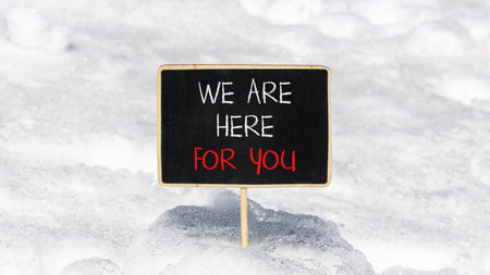 Support, help and we are here for you symbol. Concept words We are here for you on beautiful blackboard. Beautiful white snow background. Business we are here for you concept. Copy space.の写真素材