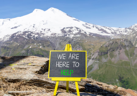 Support, help and we are here to help symbol. Concept words We are here to help on beautiful blackboard. Beautiful mountain Elbrus background. Business we are here to help concept. Copy space.の写真素材