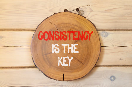 Consistency is the key symbol. Concept words Consistency is the key on beautiful wooden circle. Beautiful wooden wall background. Business consistency is the key concept. Copy space.の写真素材