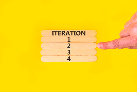 Time to iteration 2 symbol. Concept word Iteration 1 2 3 4 on wooden sticks. Businessman's hand. Yellow background. Business planning and time to iteration 2 concept. Copy space.の写真素材