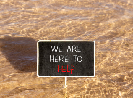 Support, help and we are here to help symbol. Concept words We are here to help on beautiful blackboard. Beautiful Red sea water background. Business we are here to help concept. Copy space.の写真素材