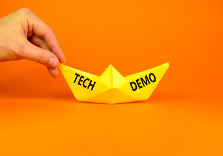 Tech demo symbol. Concept word Tech demo on beautiful yellow paper boat. Businessman's hand. Beautiful orange paper background. Business tech demo concept. Copy space.の写真素材