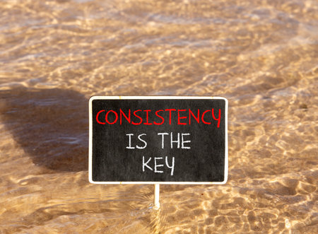 Consistency is the key symbol. Concept words Consistency is the key on beautiful blackboard. Beautiful sea water background. Business consistency is the key concept. Copy space.の写真素材