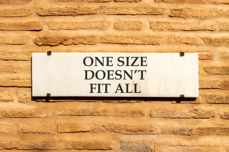 One size does not fit all symbol. Concept words One size does not fit all on beautiful white marble sign plate. Beautiful brick wall background. Business one size does not fit all concept. Copy space.の写真素材