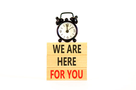 Support, help and we are here for you symbol. Concept words We are here for you on beautiful blocks. Beautiful white background. Black alarm clock. Business we are here for you concept. Copy space.の写真素材