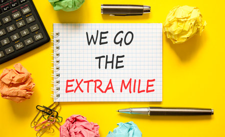 Support, help we go the extra mile symbol. Concept words We go the extra mile on beautiful white note. Beautiful yellow background. Black pen. Business we go the extra mile concept. Copy space.