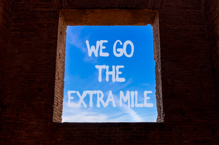 Support, help we go the extra mile symbol. Concept words We go the extra mile on beautiful window in ancient brick wall. Beautiful blue sky background. Business we go the extra mile concept Copy spaceの写真素材