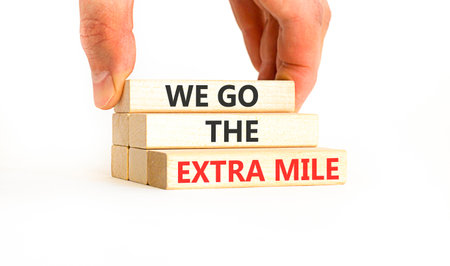 Support, help we go the extra mile symbol. Concept words We go the extra mile on beautiful wooden blocks. Beautiful white background. Business we go the extra mile concept. Copy space.の写真素材