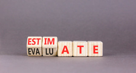 Estimate or evaluate symbol. Concept words Evaluate to Estimate on beautiful wooden cubes. Beautiful gray table gray background. Business, estimate or evaluate concept. Copy space.の写真素材