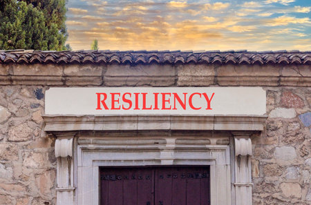 Resilience symbol. Concept word Resiliency on beautiful white marble sign plate. Beautiful ancient stone wall and sunset background. Business resiliency concept. Copy space.の写真素材