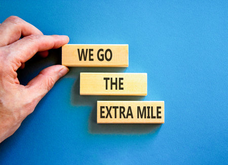 Support, help we go the extra mile symbol. Concept words We go the extra mile on beautiful wooden blocks. Beautiful blue background. Business we go the extra mile concept. Copy space.の写真素材