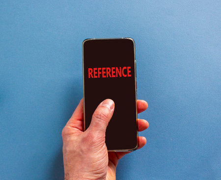 References or reference symbol. Concept word Reference on beautiful cell phone's screen in businessman's hand. Beautiful blue background. Business references or reference concept. Copy space.の写真素材