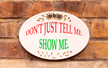 Tell or show symbol. Concept words Do not just tell me, show me beautiful white sign plate. Beautiful brick wall background. Business tell or show concept. Copy space.の写真素材
