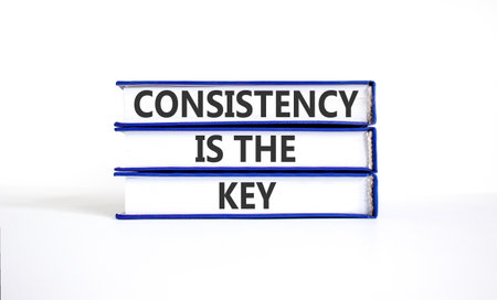 Consistency is the key symbol. Concept words Consistency is the key on beautiful books. Beautiful white paper background. Business consistency is the key concept. Copy space.の写真素材
