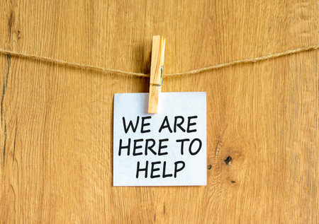 Support, help and we are here to help symbol. Concept words We are here to help on beautiful white paper on clothespin. Beautiful wooden background. Business we are here to help concept. Copy space.の写真素材