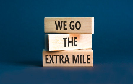Support, help we go the extra mile symbol. Concept words We go the extra mile on beautiful wooden blocks. Beautiful gray background. Business we go the extra mile concept. Copy space.の写真素材