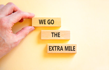 Support, help we go the extra mile symbol. Concept words We go the extra mile on beautiful wooden blocks. Beautiful white background. Business we go the extra mile concept. Copy space.の写真素材