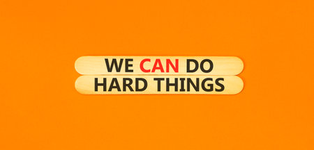 Support, help we can do hard things symbol. Concept words We can do hard things on beautiful wooden sticks. Beautiful orange background. Business we can do hard things concept. Copy space.の写真素材