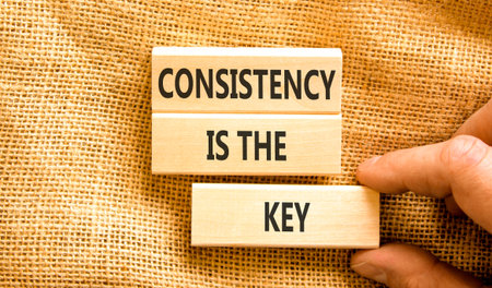Consistency is the key symbol. Concept words Consistency is the key on beautiful wooden blocks. Beautiful canvas background. Businessman's hand. Business consistency is the key concept. Copy space.の写真素材