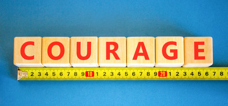 Courage symbol. Concept word Courage on beautiful wooden blocks. Beautiful blue background. Beautiful yellow ruler. Business courage concept. Copy space.の写真素材