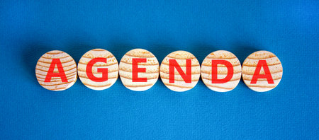 Agenda symbol. Concept word Agenda on beautiful wooden circles. Beautiful blue background. Business agenda concept. Copy space.の写真素材