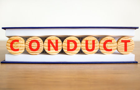 Conduct symbol. Concept word Conduct on beautiful wooden circles in book. Beautiful wooden table white background. Business conduct concept. Copy space.の写真素材