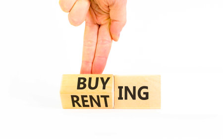 Buying or renting symbol. Concept words Buying or Renting on beautiful wooden cubes. Beautiful white background. Businessman's hand. Business, buying or renting concept. Copy space.の写真素材