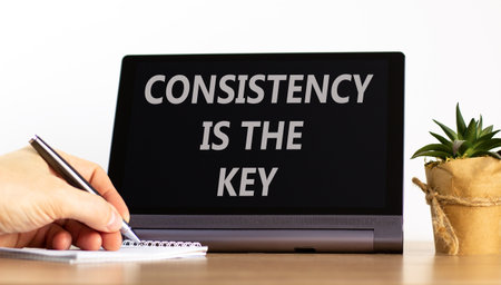 Consistency is the key symbol. Concept words Consistency is the key on beautiful black tablet. Beautiful white background. Businessman's hand. Business consistency is the key concept. Copy space.の写真素材