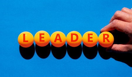 Leadership and leader symbol. Concept word Leader on beautiful orange table tennis ping pong balls. Beautiful blue background. Businessman's hand. Business leader and leadership concept. Copy space.の写真素材