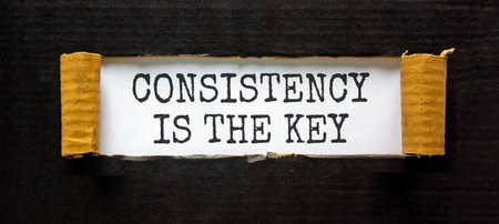 Consistency is the key symbol. Concept words Consistency is the key on beautiful white paper. Beautiful black paper background. Business consistency is the key concept. Copy space.の写真素材