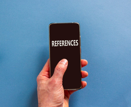 References or reference symbol. Concept word References on beautiful cell phone's screen in businessman's hand. Beautiful blue background. Business references or reference concept. Copy space.の写真素材